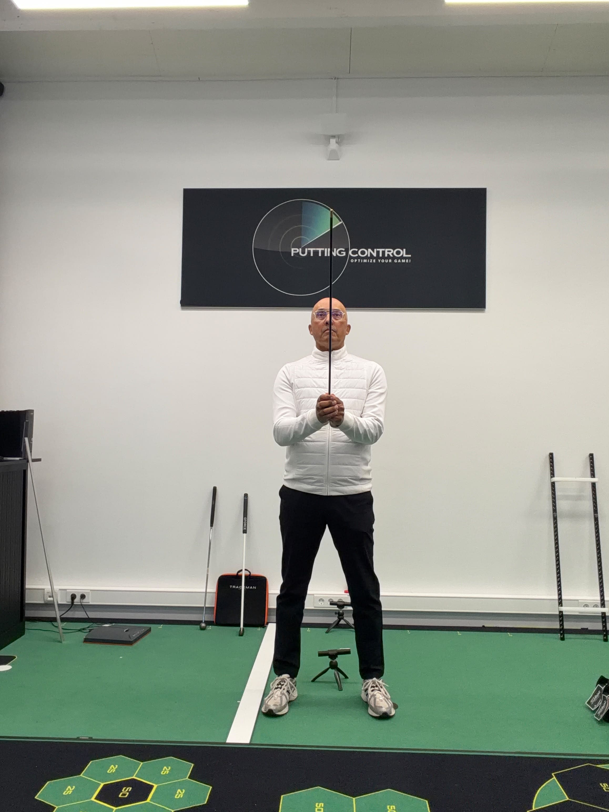 Raymond demonstrates the dominant-eye test holding a putter upright