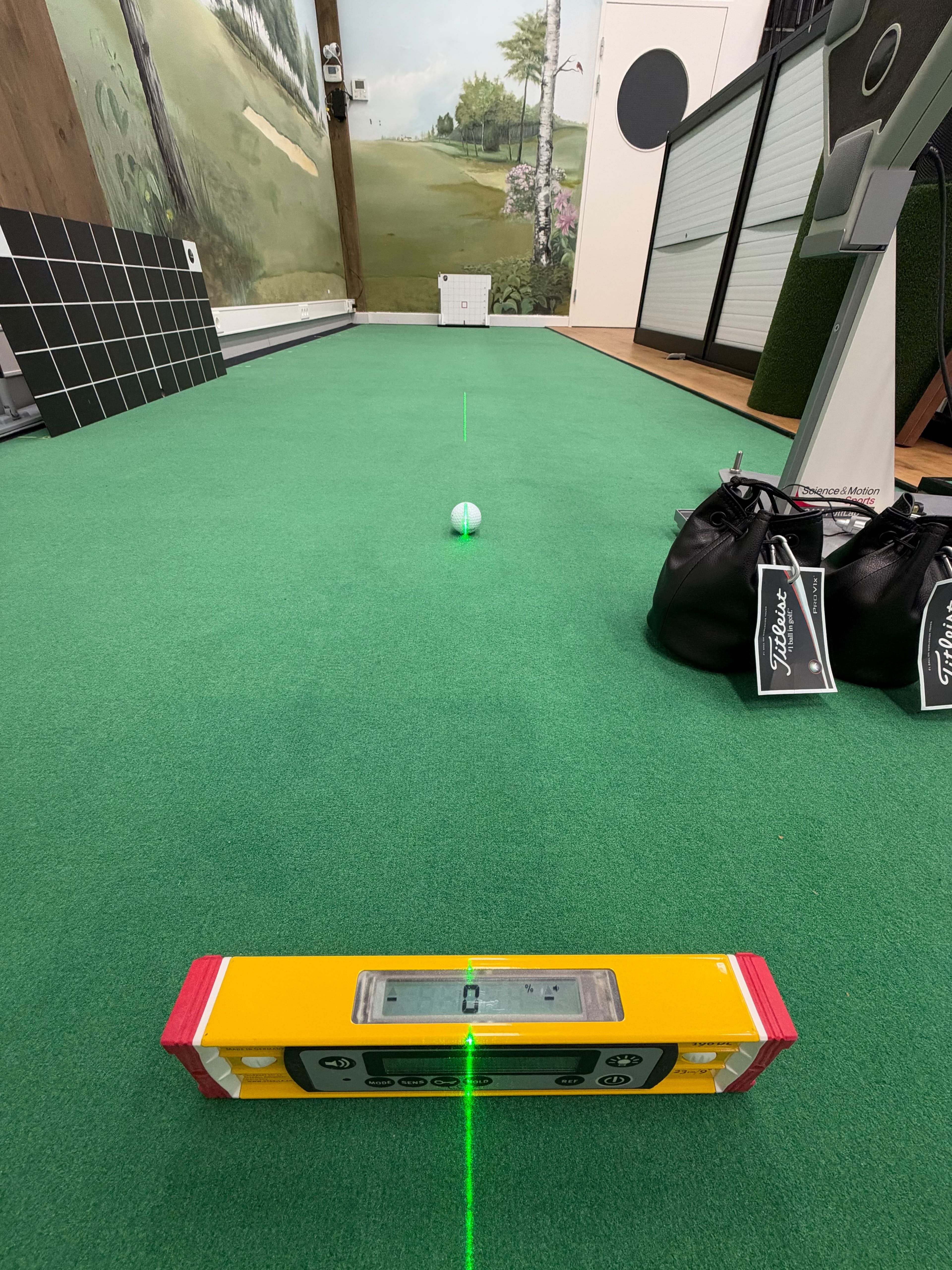 Digital spirit level showing zero on the putting surface, aligned with a green laser